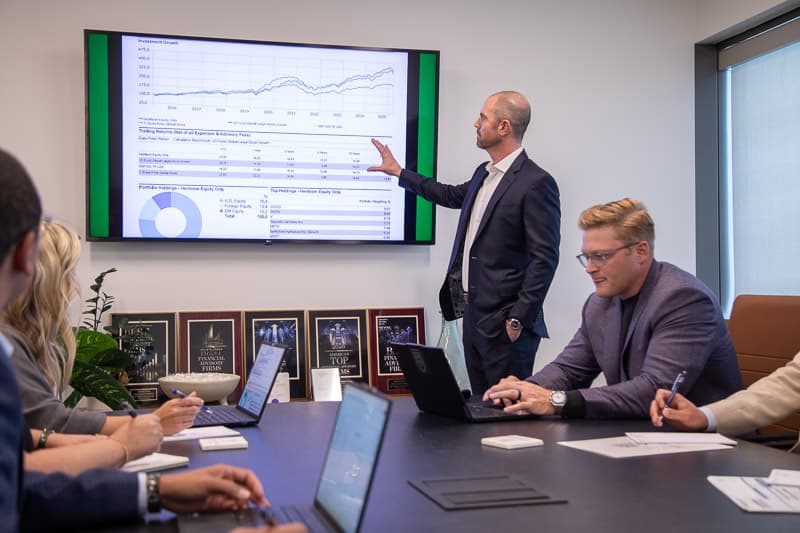 A Heirloom advisor presenting audited investment performance charts to the team in a conference room