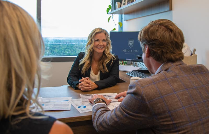 A Heirloom advisor smiling with a couple across the desk during a planning conversation