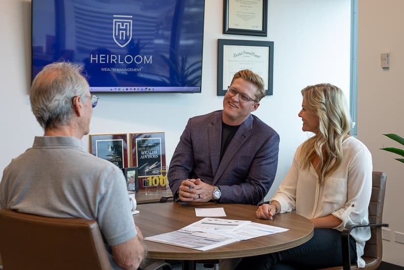A Heirloom advisor team meeting with a client in front of the Heirloom Wealth Management brand wall